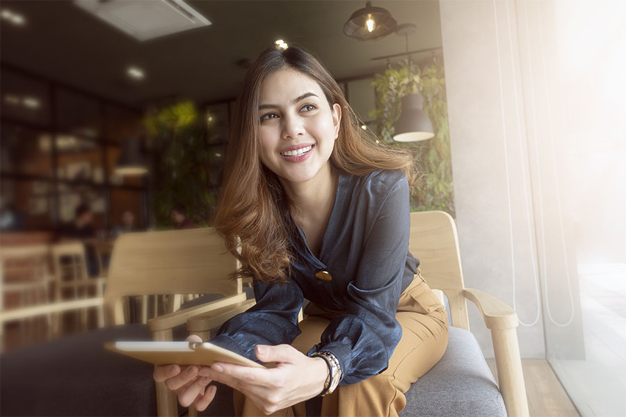 Contact - Smiling Businesswoman Sitting in Cafe Looking Out Window with a Tablet